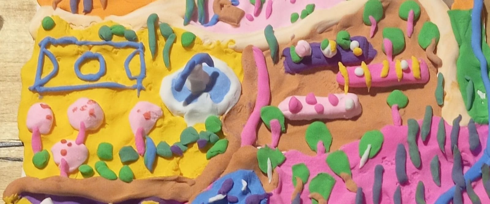 Maqueta de una ciudad modelada en plastilina: calles, ríos, árboles, casas y huertos de colores